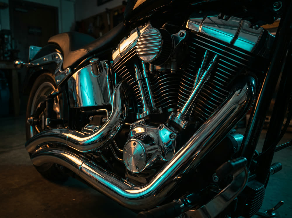 Close-up of a chrome motorcycle engine with teal and amber lighting